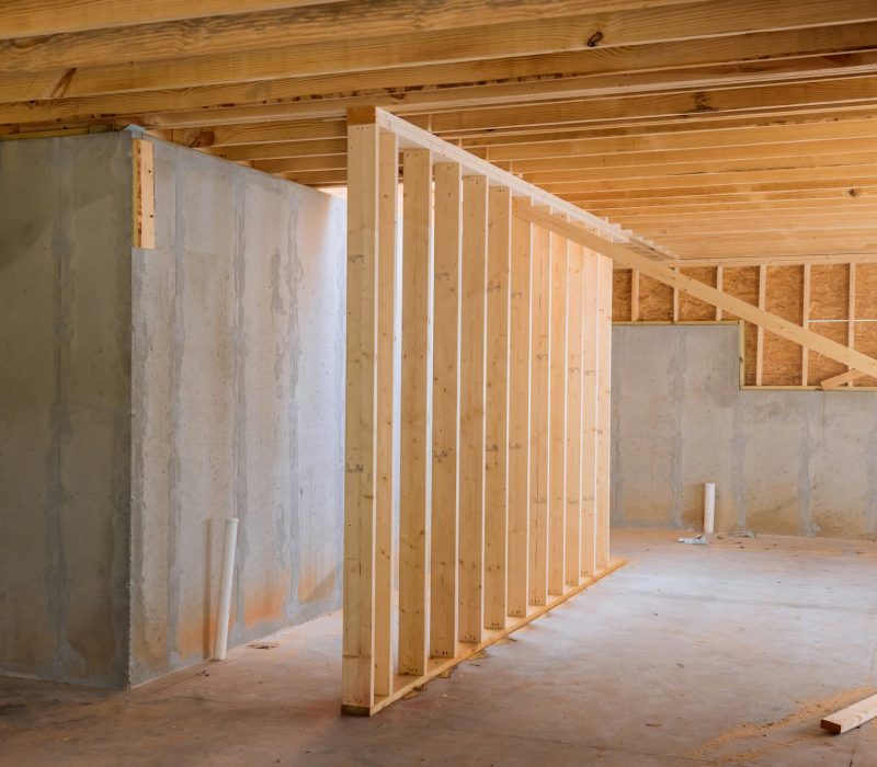 A house with wooden framework frame that is under construction is supported by beams during